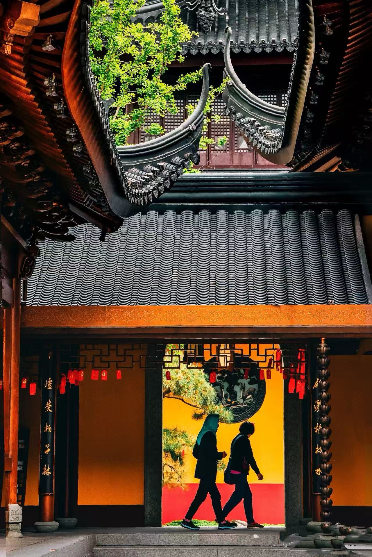 Traditional temple rooflines and visitors walking through a courtyard at Jade Buddha Temple