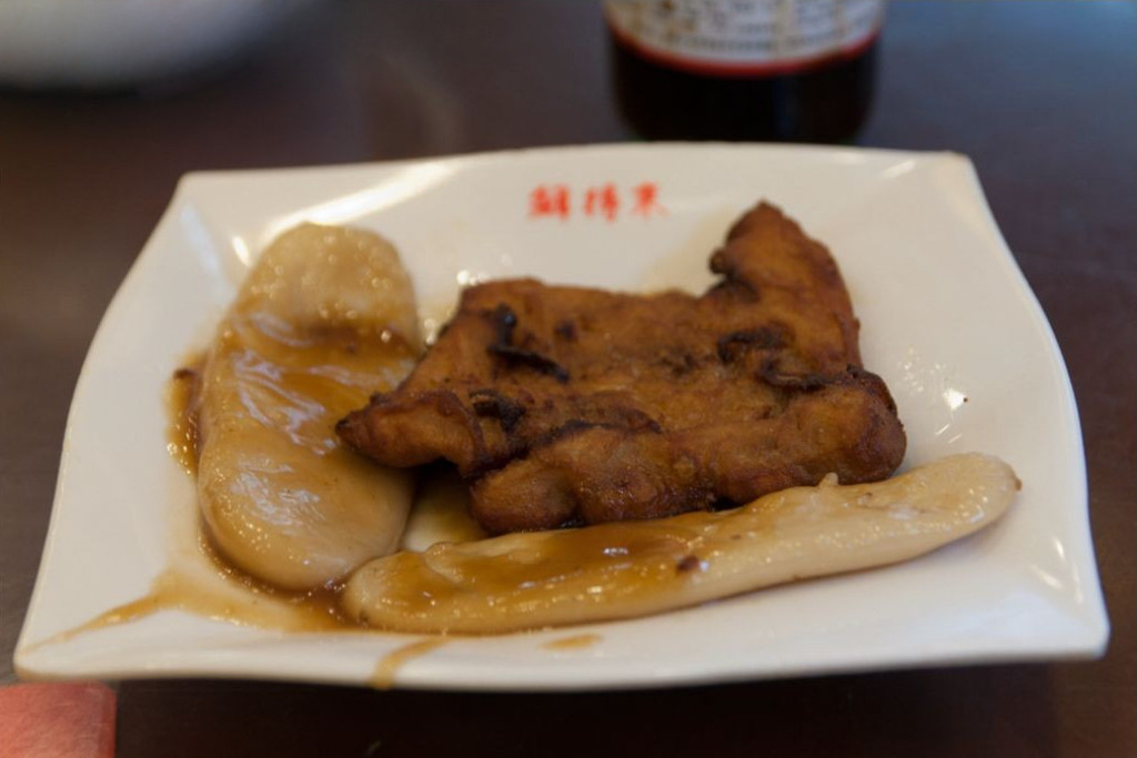 Fried pork chop and sauced rice cakes on a white plate at Xian De Lai